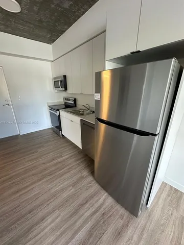 a kitchen with granite countertop a refrigerator and wooden floor