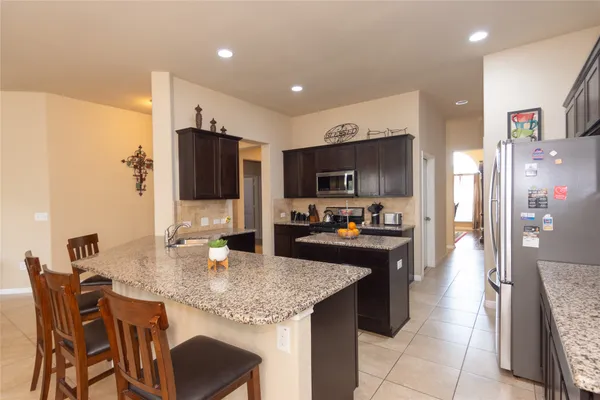 a kitchen with stainless steel appliances granite countertop a sink refrigerator and cabinets