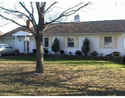 a front view of house with yard and trees in the background