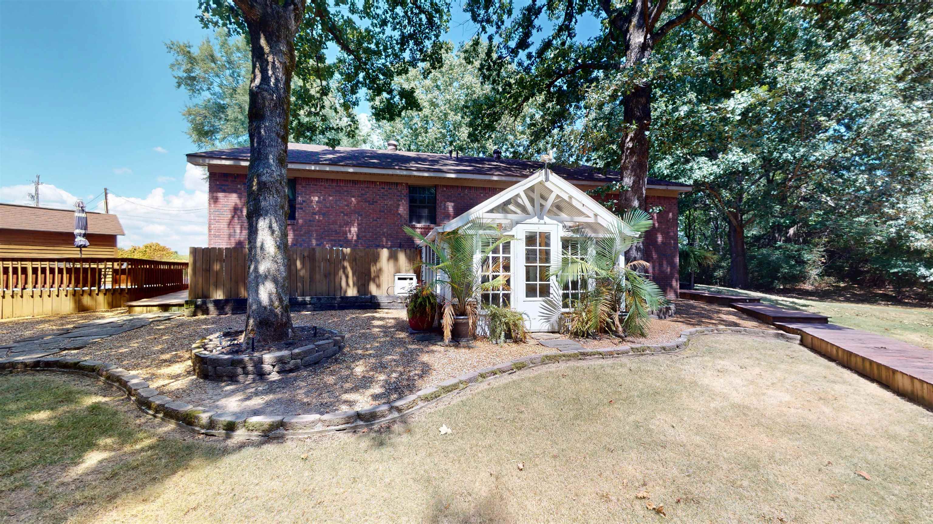 420 Joann Road Somerville, TN 38068 - Photo 31 of 40 Brick exterior, wood-plank deck, white-framed sunroom, mature trees, and a landscaped yard