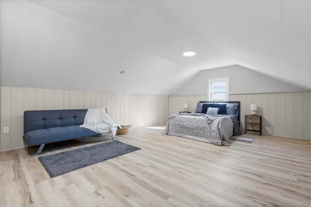 a spacious bedroom with a bed and wooden floor