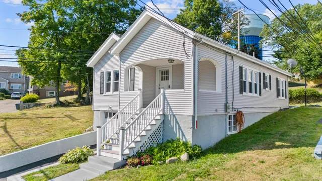 a view of a white house next to a yard with potted plants