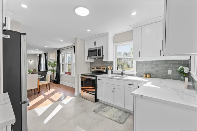 a kitchen with stainless steel appliances granite countertop a sink stove refrigerator and cabinets