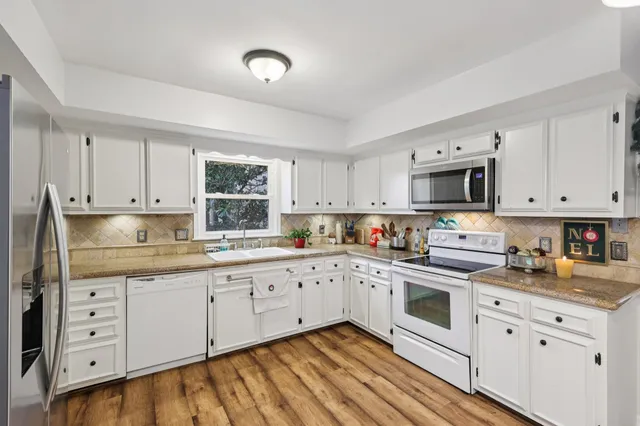 a kitchen with granite countertop white cabinets white stainless steel appliances with a sink and dishwasher