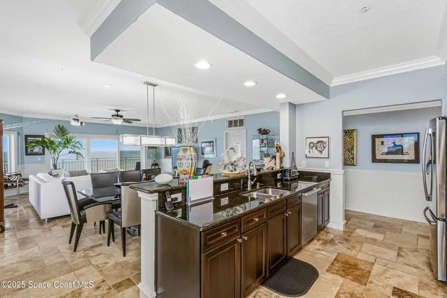 a kitchen with stainless steel appliances granite countertop a stove a sink a refrigerator and chairs