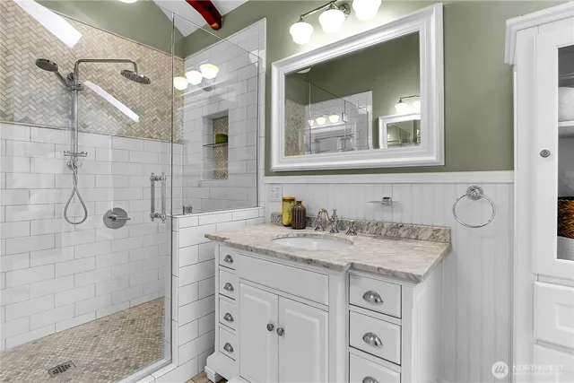 a bathroom with a granite countertop sink a mirror and shower