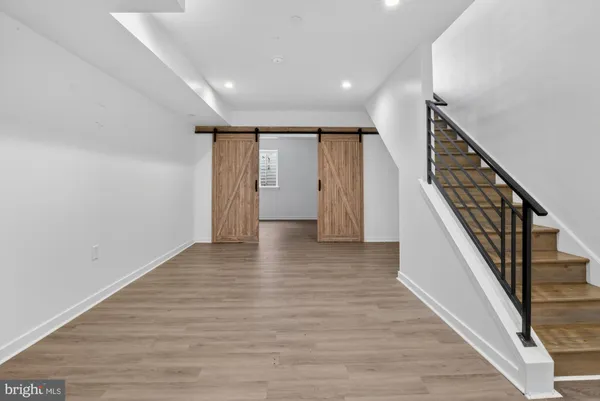 a view of an empty room with wooden floor and stairs