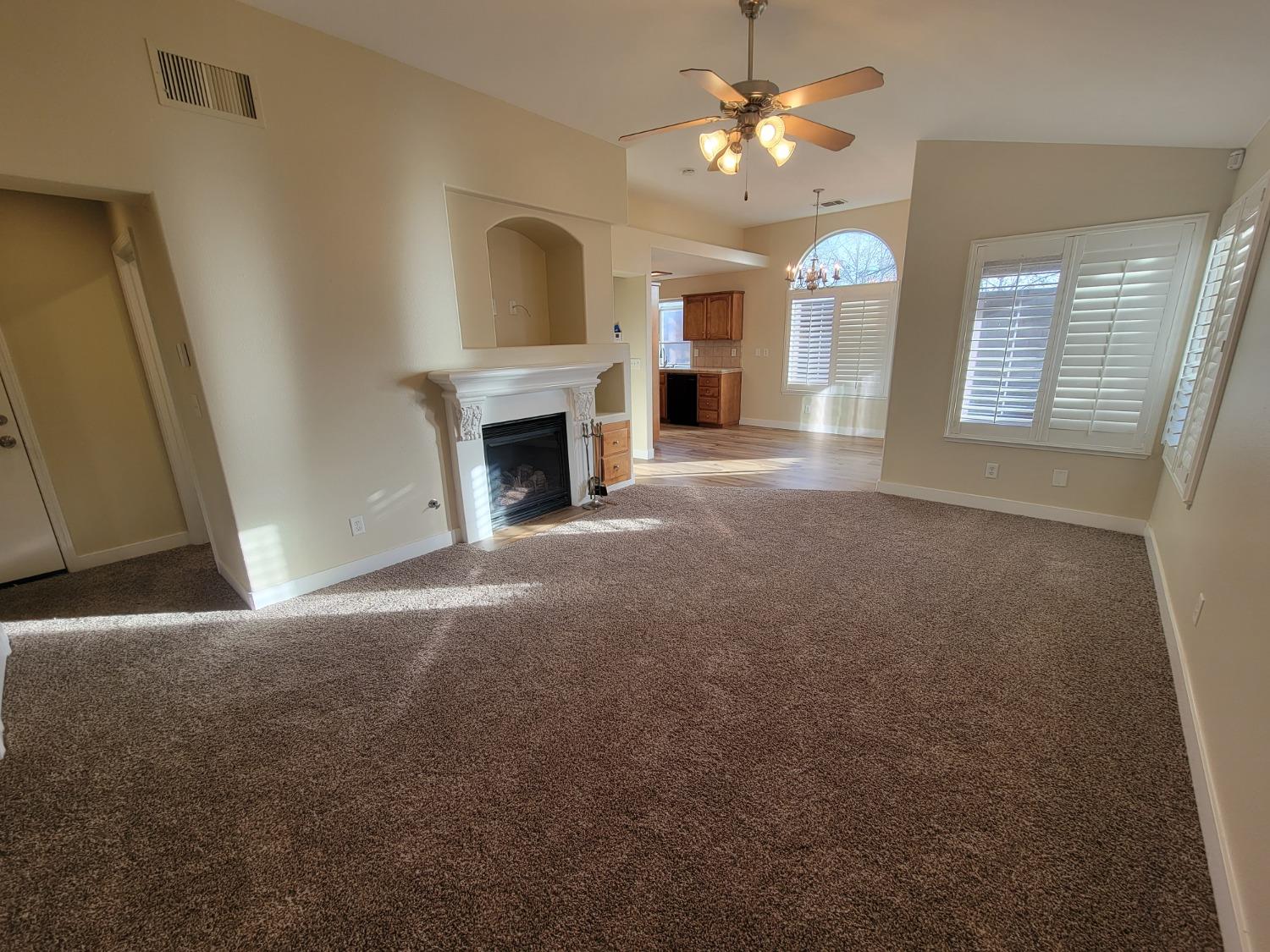 2831 Isabel Avenue Clovis, CA 93611 - Photo 5 of 27 a view of a livingroom with a fireplace a ceiling fan and windows
