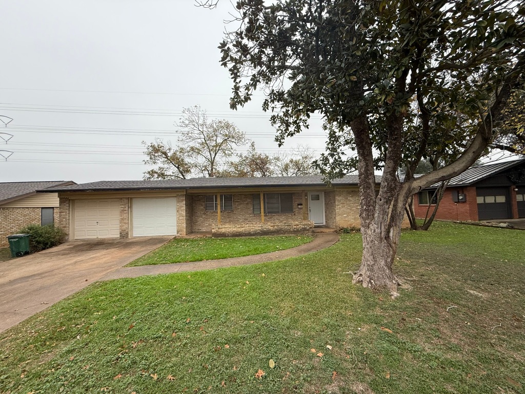 Single story home featuring concrete driveway, a front lawn, an attached garage, and brick siding