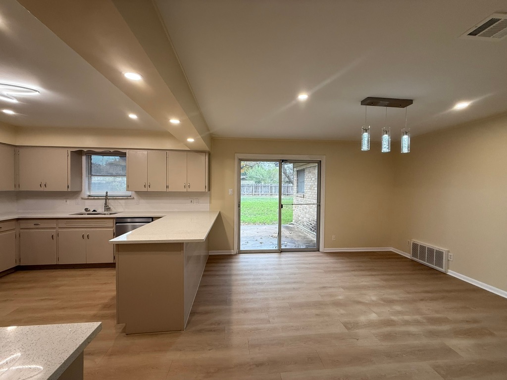 4603 Roundup Trail Austin, TX 78745 - Photo 20 of 35 Kitchen featuring recessed lighting, a peninsula, light wood-style floors, healthy amount of natural light, and pendant lighting