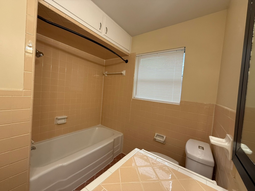 4603 Roundup Trail Austin, TX 78745 - Photo 26 of 35 Full bathroom featuring tile walls, bathtub / shower combination, and wainscoting