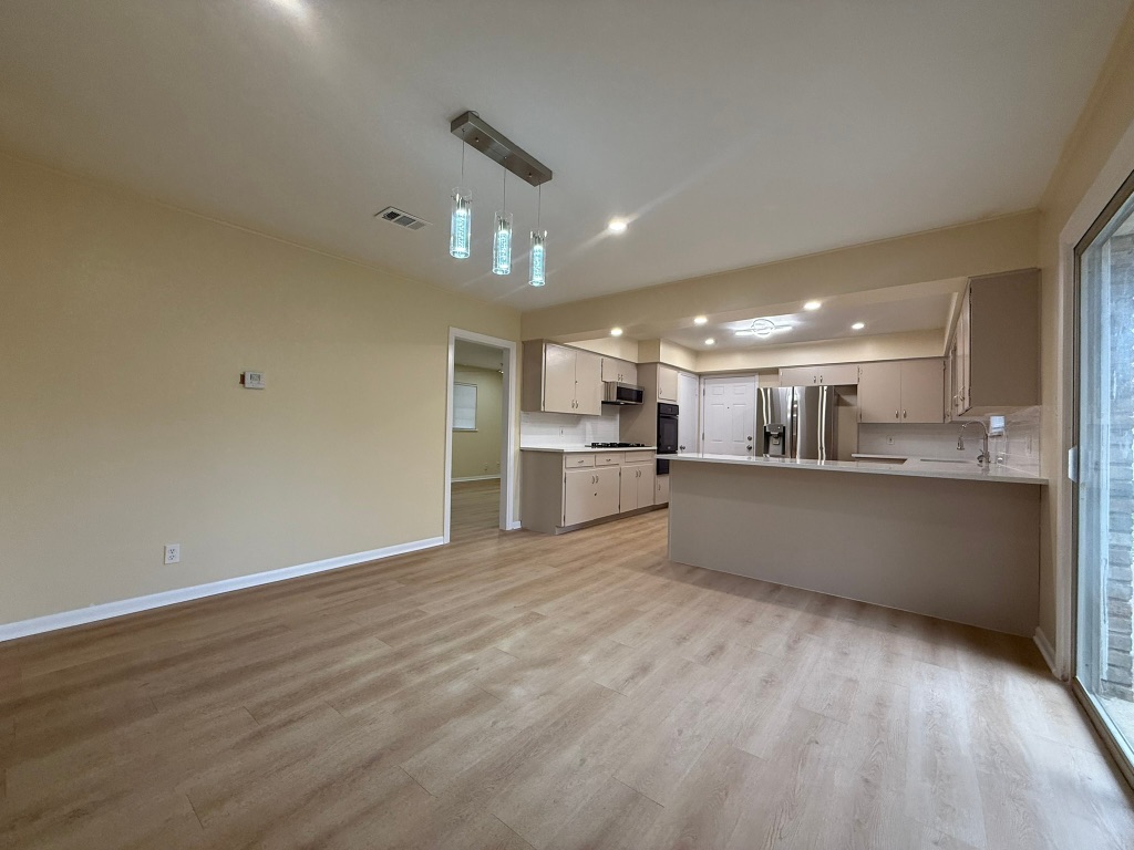 4603 Roundup Trail Austin, TX 78745 - Photo 35 of 35 Kitchen with a peninsula, light countertops, light wood-style flooring, stainless steel refrigerator with ice dispenser, and open floor plan