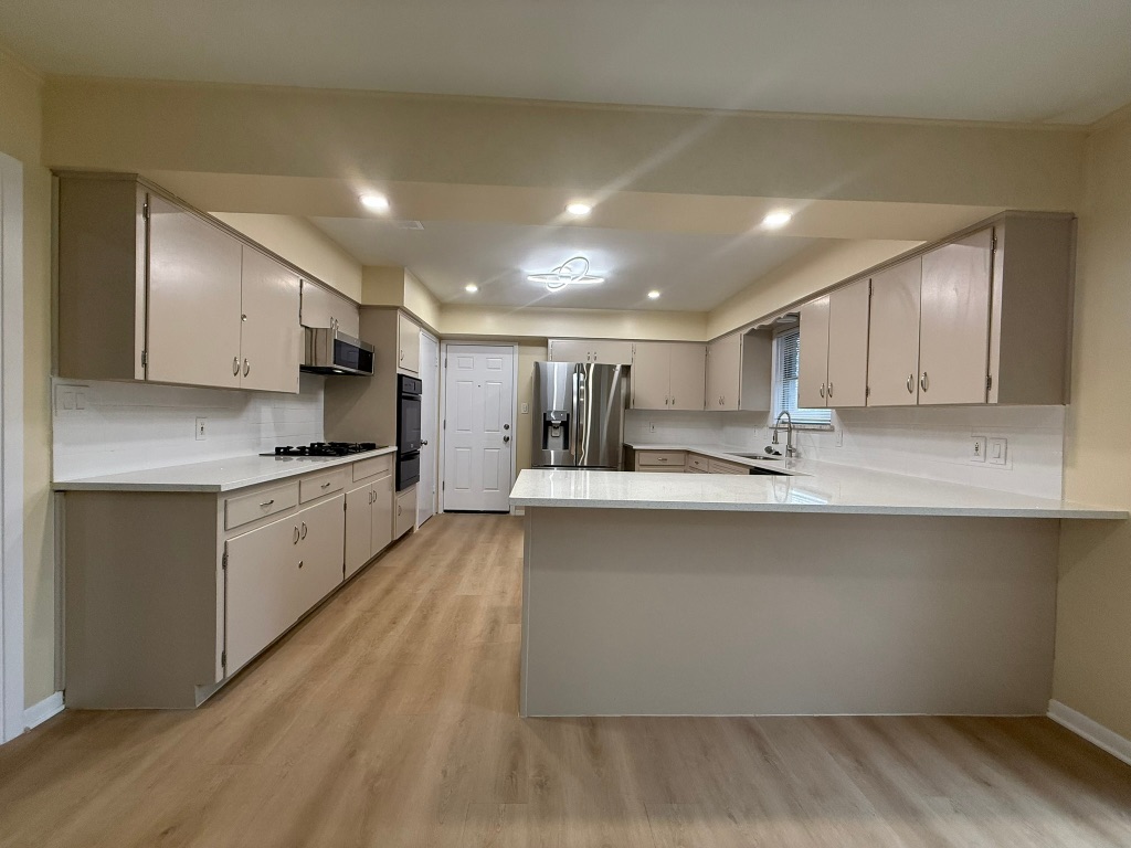 4603 Roundup Trail Austin, TX 78745 - Photo 7 of 35 Kitchen with a peninsula, appliances with stainless steel finishes, light wood-type flooring, recessed lighting, and decorative backsplash