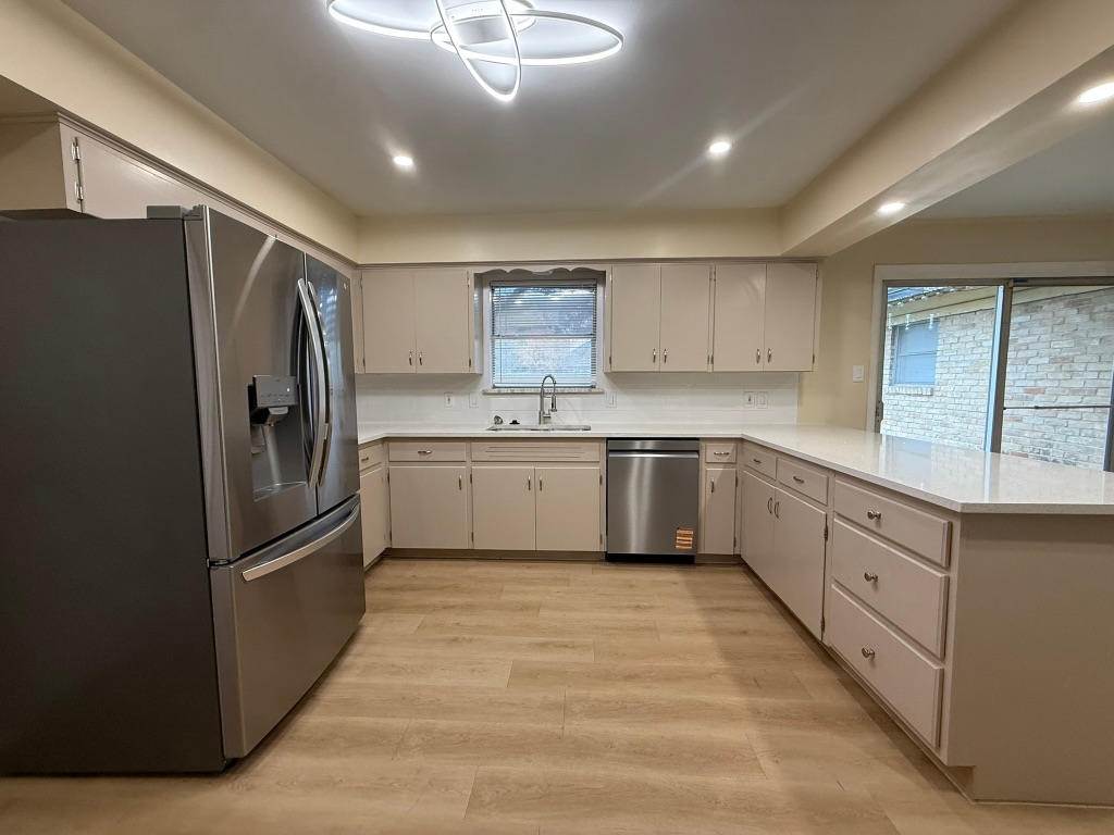 4603 Roundup Trail Austin, TX 78745 - Photo 8 of 35 Kitchen with appliances with stainless steel finishes, light wood-style flooring, a peninsula, backsplash, and recessed lighting