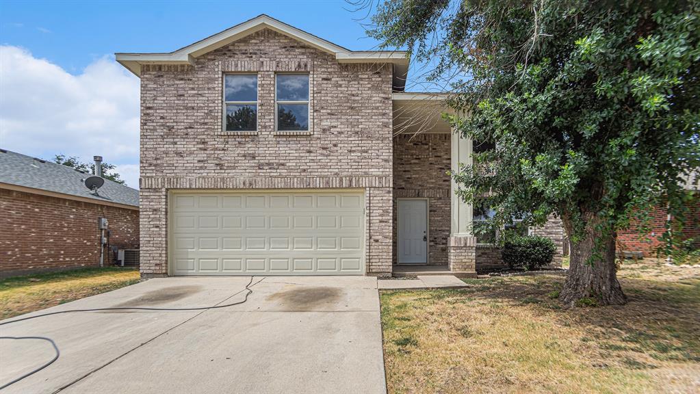 Traditional home featuring an attached garage, brick siding, and concrete driveway