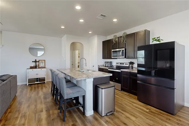 a kitchen with stainless steel appliances a stove a sink a microwave a refrigerator and cabinets