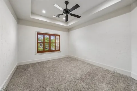 an empty room with windows and ceiling fan