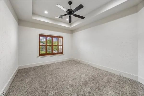 an empty room with windows and ceiling fan