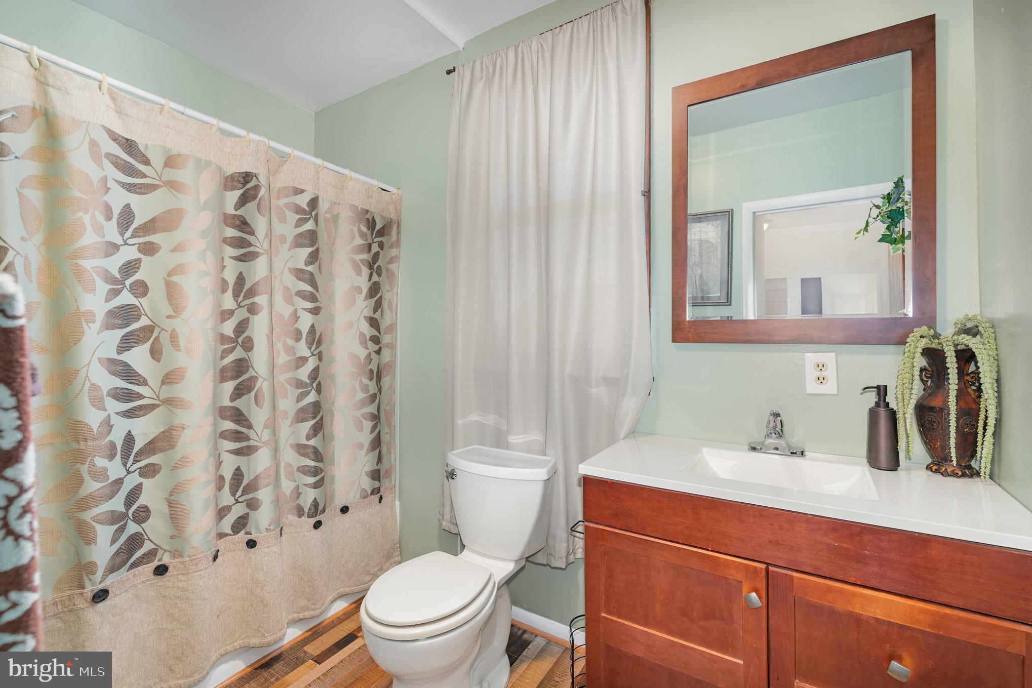 5005 Catalpha Road Baltimore, MD 21214 - Photo 23 of 31 a bathroom with a sink a toilet and shower curtain