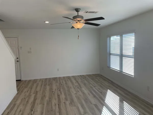 a view of wooden floor and a chandelier fan in a room