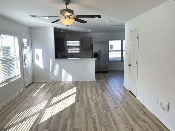a view of hallway with wooden floor and a ceiling fan