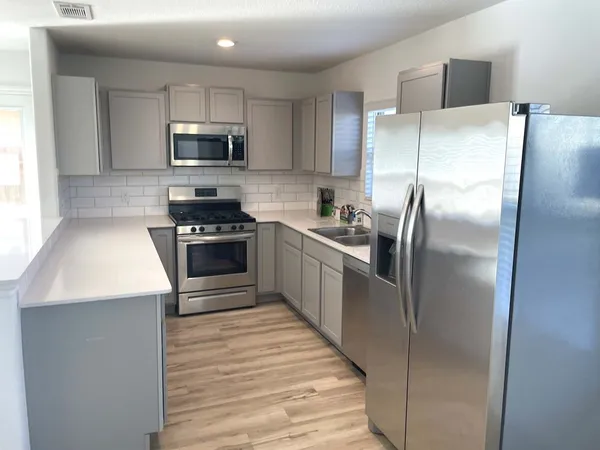 a kitchen with stainless steel appliances granite countertop a refrigerator a stove a sink and a microwave