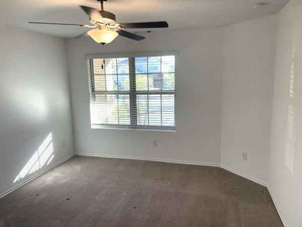 an empty room with a window and a fan