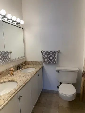 a bathroom with a granite countertop sink a toilet and a mirror