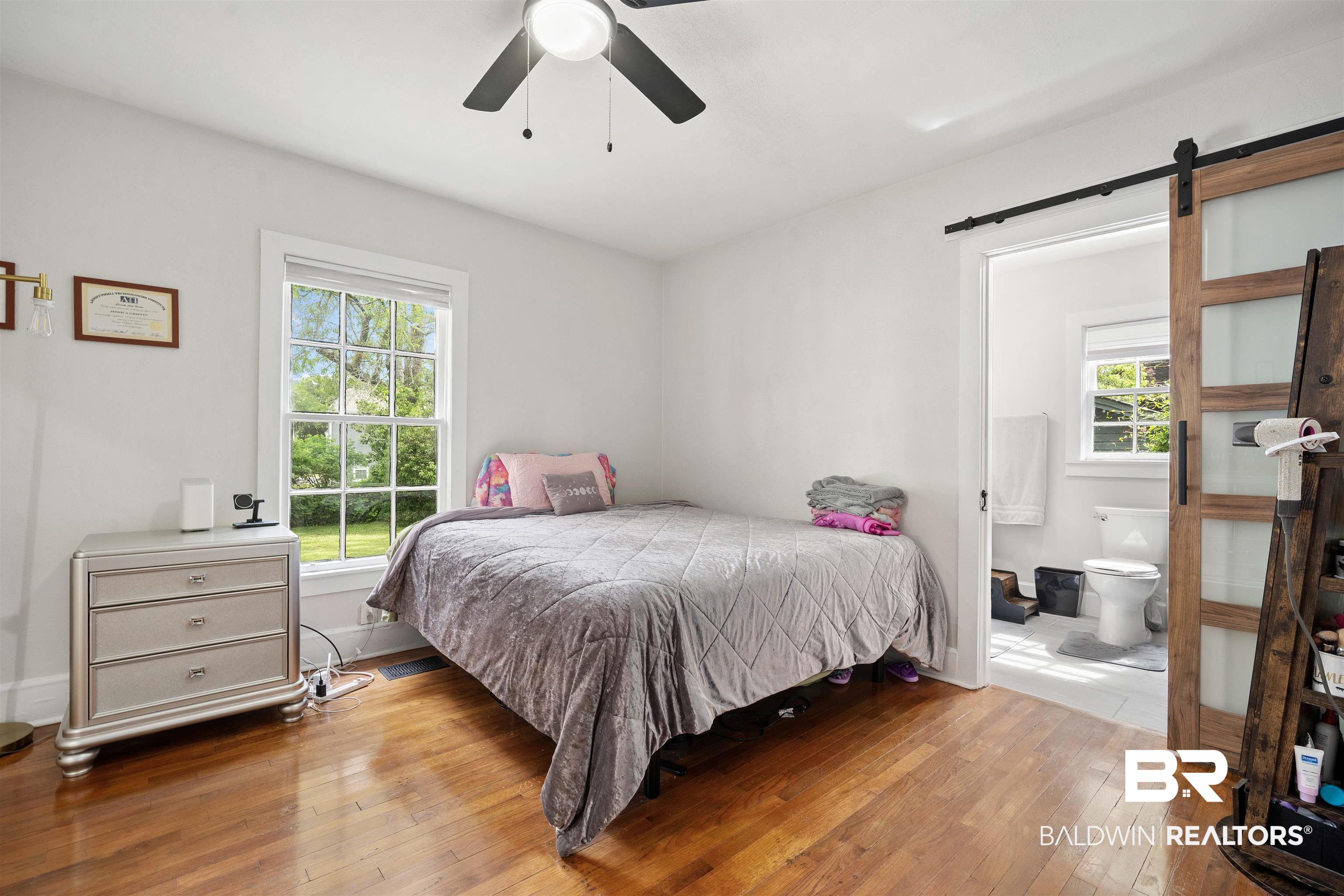 103 Emogene Place Mobile, AL 36606 - Photo 16 of 32 Bedroom with a barn door, light wood finished floors, ceiling fan, and ensuite bath