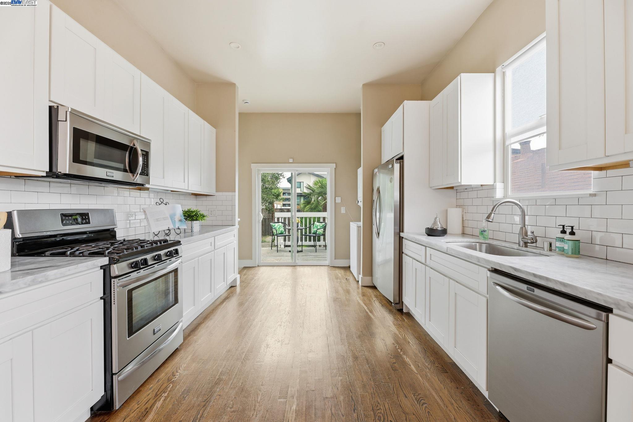 2417 Linden Street Oakland, CA 94607 - Photo 16 of 41 a kitchen with stainless steel appliances a white cabinets a sink a stove a microwave and wooden floors
