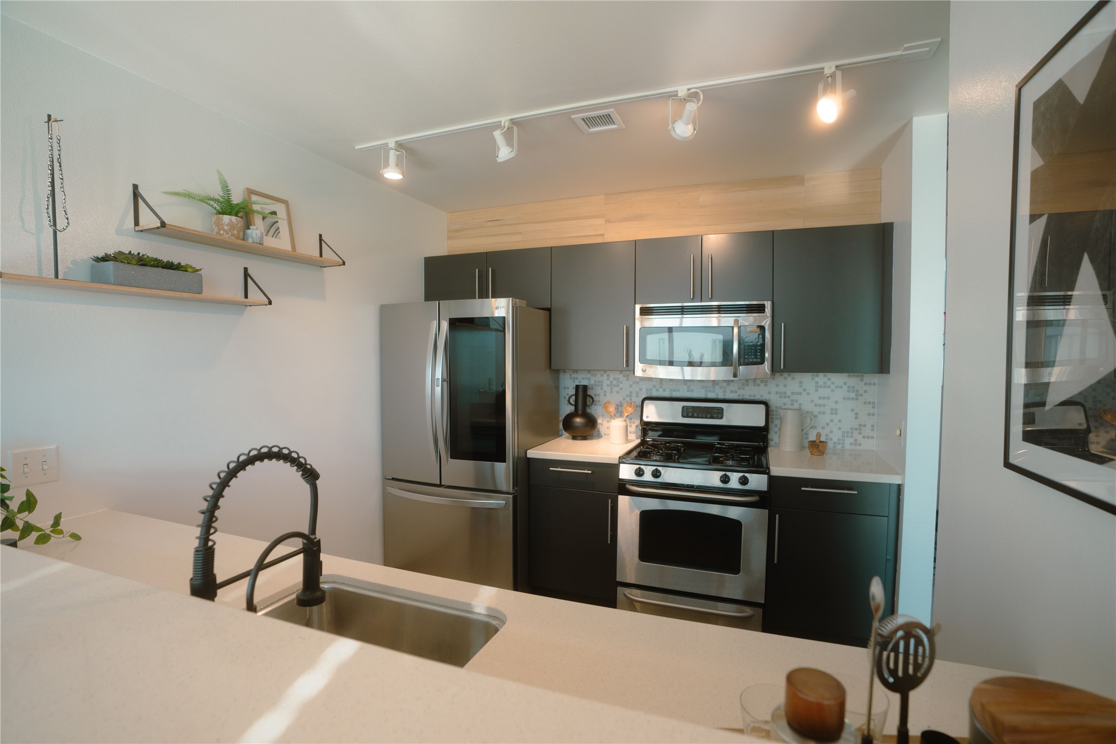 4801 South Congress Avenue, Unit H5 Austin, TX 78745 - Photo 15 of 39 Kitchen featuring stainless steel appliances, track lighting, backsplash, open shelves, and modern cabinets