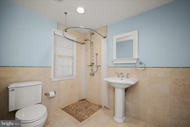 a spacious bedroom with a bed mirror dresser and a chandelier