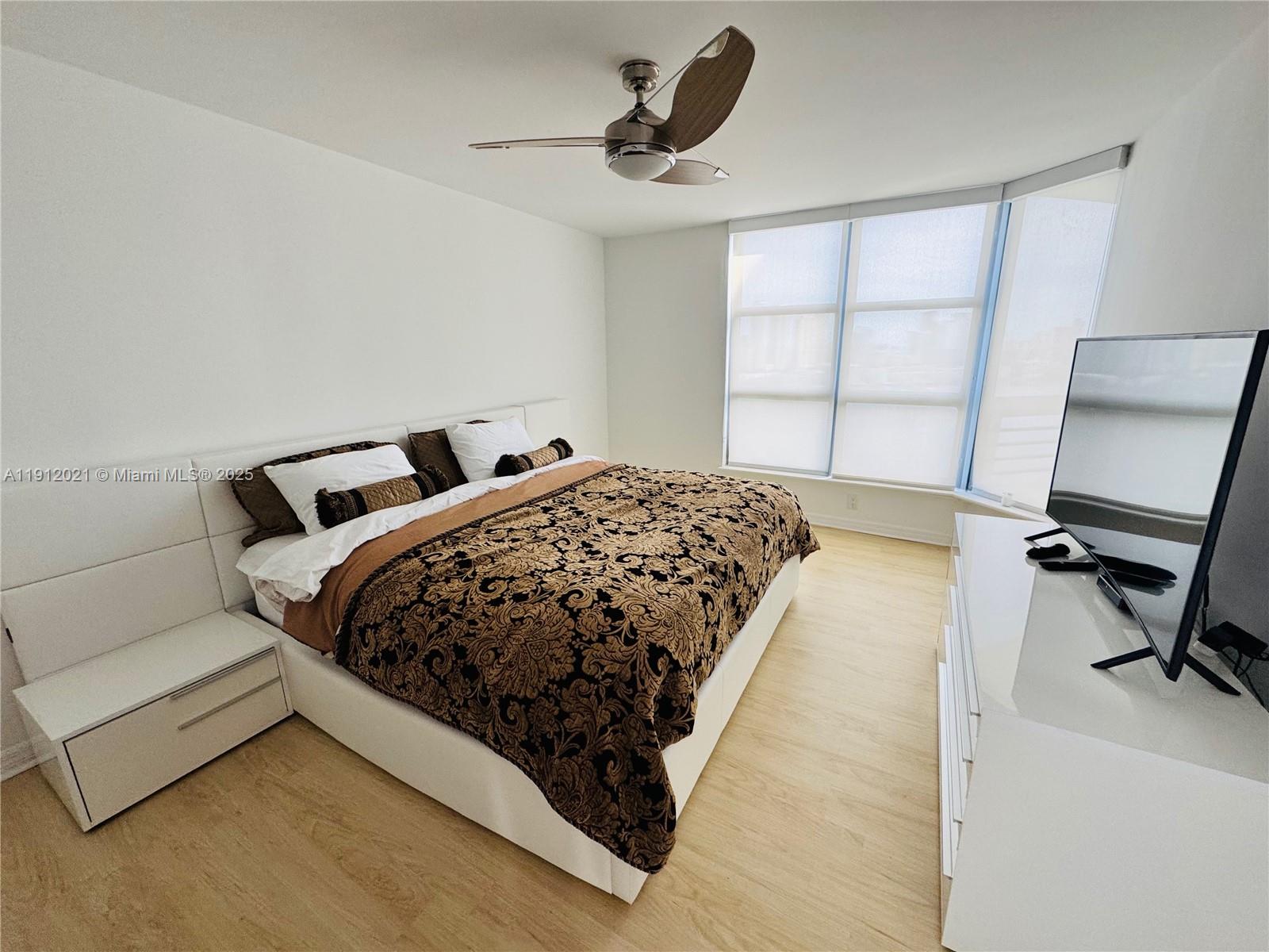 3530 Mystic Pointe Drive, Unit 3111 Aventura, FL 33180 - Photo 13 of 22 a bed sitting in a bedroom next to a window