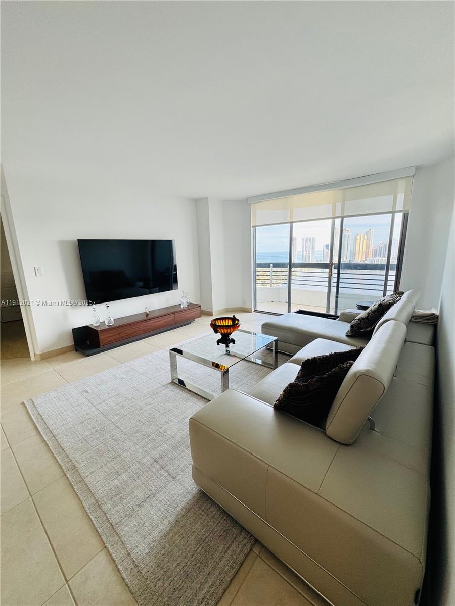 3530 Mystic Pointe Drive, Unit 3111 Aventura, FL 33180 - Photo 4 of 22 a living room with furniture and a flat screen tv