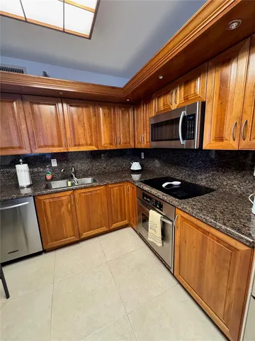 a kitchen with granite countertop a stove a sink and a microwave