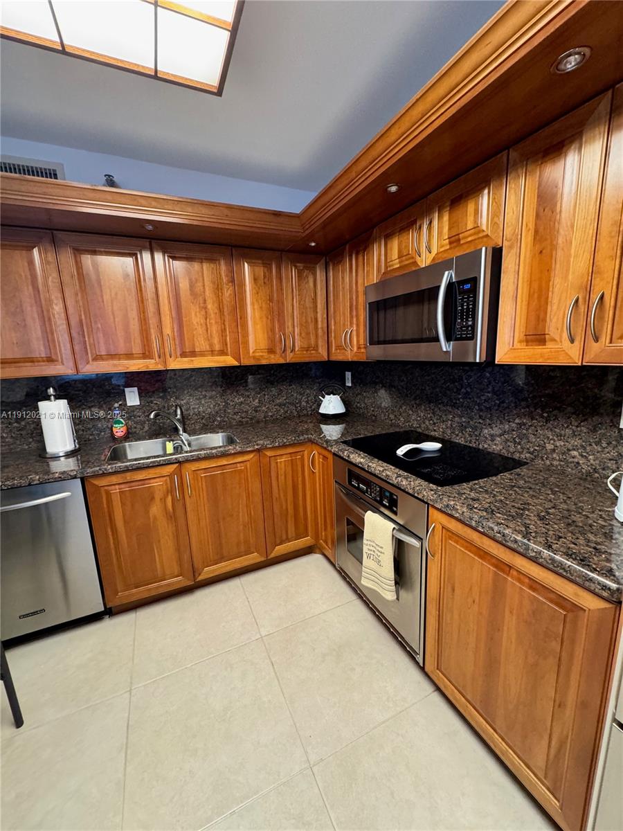 3530 Mystic Pointe Drive, Unit 3111 Aventura, FL 33180 - Photo 5 of 22 a kitchen with granite countertop a stove a sink and a microwave