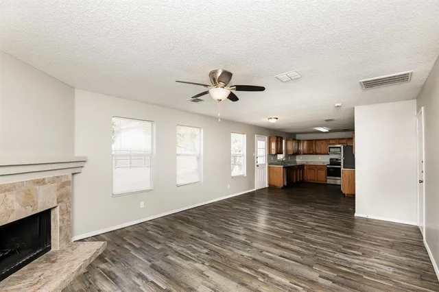 a view of an empty room with window and a kitchen