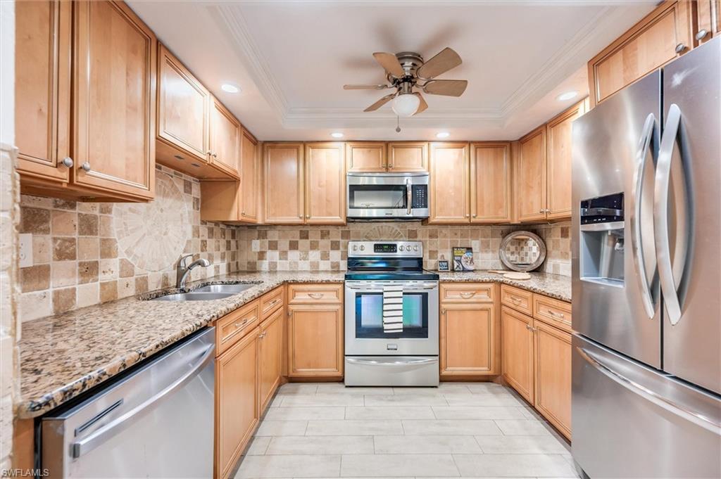 940 Augusta Boulevard, Unit D939 Naples, FL 34113 - Photo 16 of 42 a kitchen with kitchen island granite countertop a sink stainless steel appliances and counter space