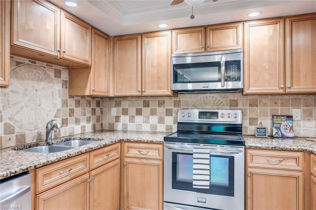 940 Augusta Boulevard, Unit D939 Naples, FL 34113 - Photo 17 of 42 a kitchen with granite countertop a stove a sink and a microwave