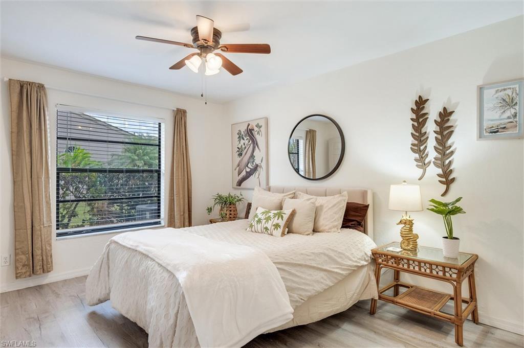 940 Augusta Boulevard, Unit D939 Naples, FL 34113 - Photo 26 of 42 a bedroom with a bed a mirror and a large window