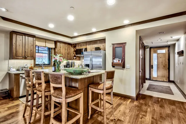 a room with stainless steel appliances kitchen island granite countertop a table and chairs in it