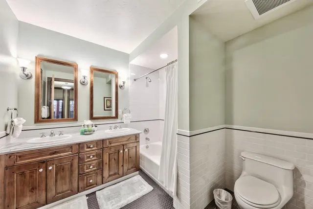 a spacious bathroom with a granite countertop sink toilet a large mirror a shower and vanity