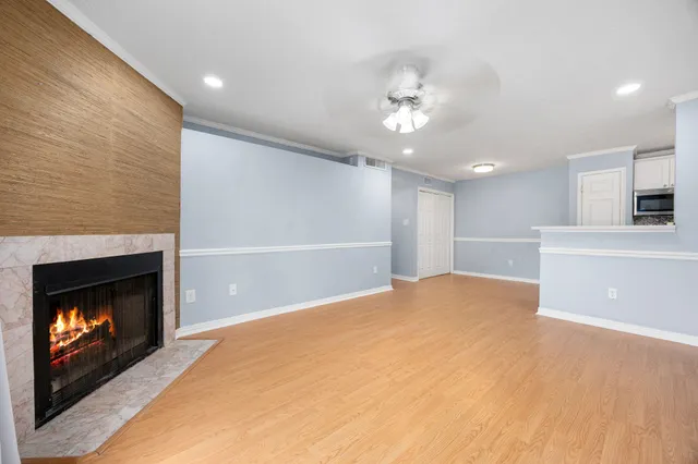 a view of an empty room with kitchen and fireplace