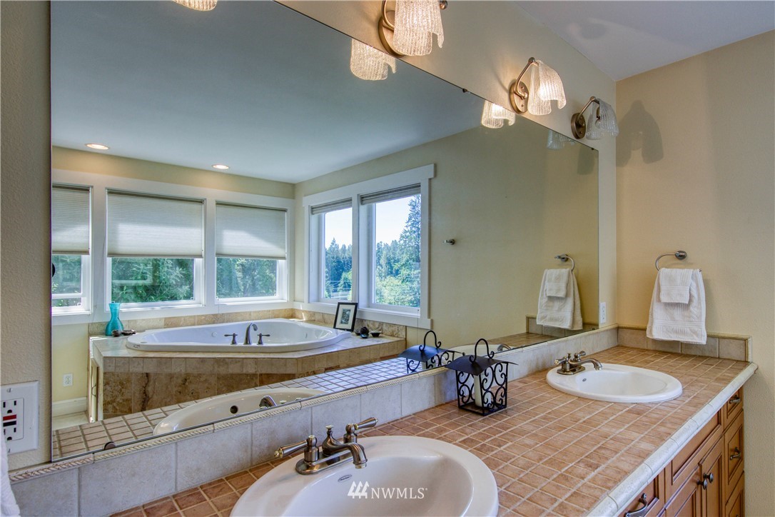 20821 Miller Bay Road Northeast Poulsbo, WA 98370 - Photo 23 of 40 a bathroom with a tub a sink and mirror