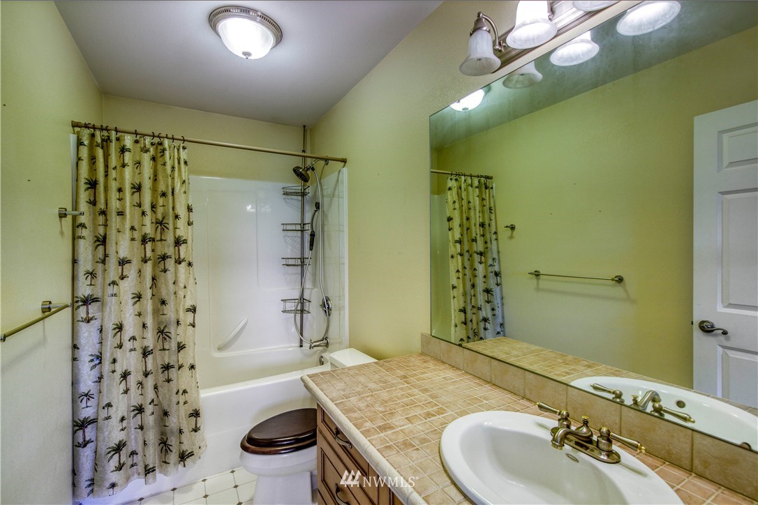 20821 Miller Bay Road Northeast Poulsbo, WA 98370 - Photo 31 of 40 a bathroom with a granite countertop sink a toilet a mirror and shower