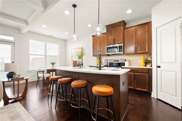 a kitchen with stainless steel appliances granite countertop a stove a sink a microwave a island with a dining table and chairs