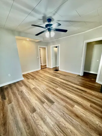 a view of an empty room with window and wooden floor