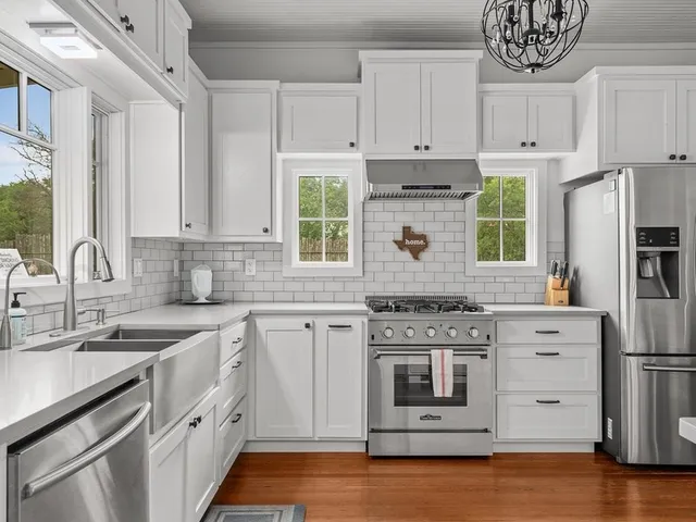a kitchen with stainless steel appliances granite countertop a stove and white cabinets