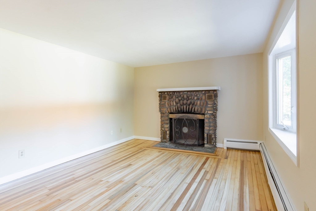 137 Lowell Road Pepperell, MA 01463 - Photo 13 of 40 a view of an empty room with wooden floor fireplace and a window
