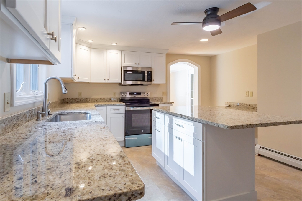 137 Lowell Road Pepperell, MA 01463 - Photo 4 of 40 a large kitchen with kitchen island granite countertop a stove top oven a sink a counter space and cabinets
